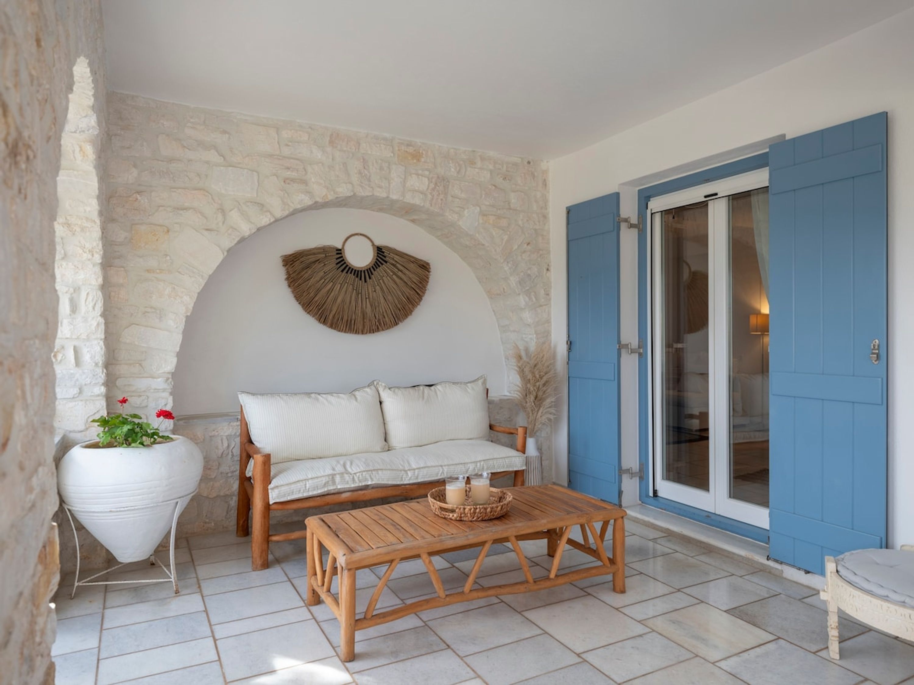 A cozy room with a stone wall, a white sofa, a wooden coffee table, and a blue door.