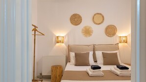 A neatly arranged bedroom with a bed, bedside lamps, and a ceiling fan. - Sunrise Serenity Near Ambelas Beach (Paros)