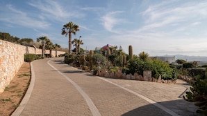 A paved pathway with stone walls and palm trees, leading to a building with a dome roof. - Villa Franca Ideal for Wedding Parties (Paros)