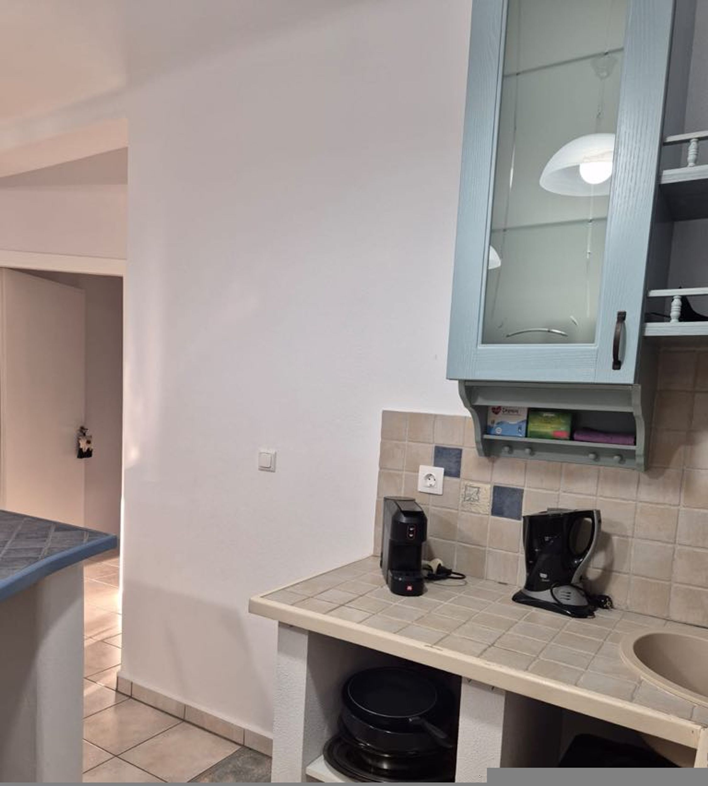 A small kitchenette with a countertop, a coffee maker, a kettle, and a microwave.