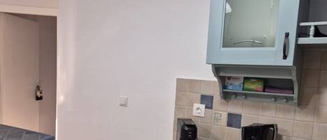 A small kitchenette with a countertop, a coffee maker, a kettle, and a microwave.