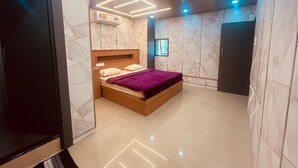 A modern bedroom with a wooden bed, a built-in wardrobe, and a marble-patterned wall. - Spexxa Residency (Kozhikode)