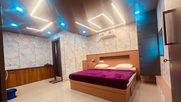 A modern bedroom with a bed, built-in wardrobe, and a bathroom with a shower and sink. - Spexxa Residency (Kozhikode)
