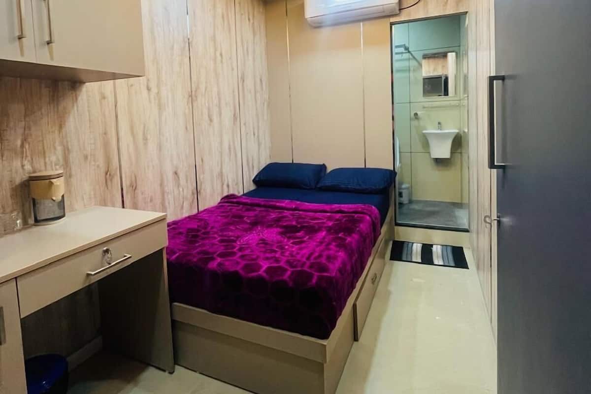 A compact bedroom with a bed, bedside table, and a built-in wardrobe.