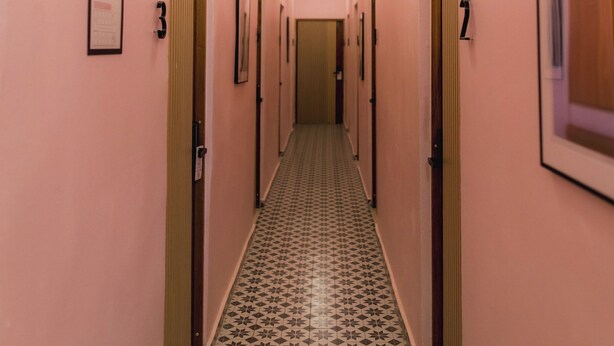 Een gang met deuren genummerd 3 en 7, die naar kamers leiden.