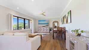 A spacious living area with a sofa, dining table, and kitchen counter.