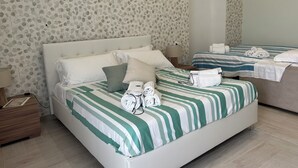 Una habitación de hotel con una cama grande, una cama más pequeña y una mesita de noche con una lámpara.