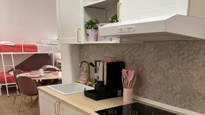 A modern kitchen with a built-in stove, white cabinets, and a dining area with a red chair and table. - B&B Elegance (Villa San Giovanni)