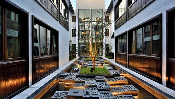 A modern building with a central courtyard featuring a tree and illuminated ground panels. - Meshee Sezen Hotel Suzhou (Suzhou)