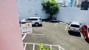 A hotel parking lot with marked spaces, a sign for 'HOTEL LUZ', and potted plants. - Room 12: Sunlit Balcony Stay Near Calle Cerra (San Juan)