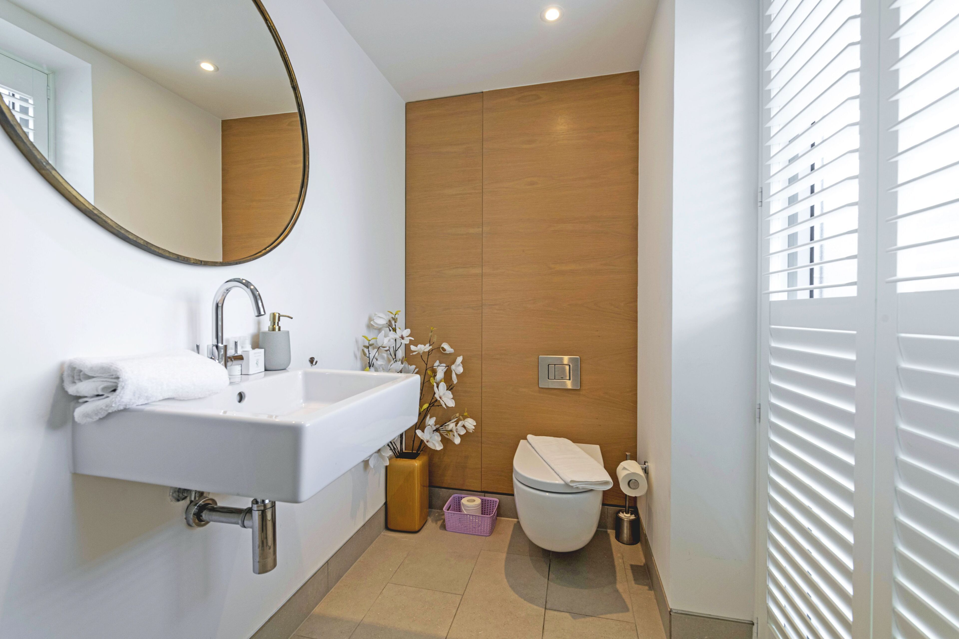 A modern bathroom with a white sink, mirror, and toilet.