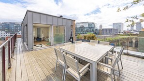 Une terrasse extérieure moderne avec une pièce fermée par des baies vitrées, une table en bois et des chaises.