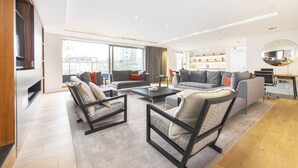 Un salon moderne comprenant un canapé, des fauteuils, une table basse et un téléviseur.
