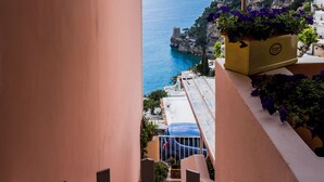 Een trap leidt naar een balkon met uitzicht op de kust onder een heldere lucht.