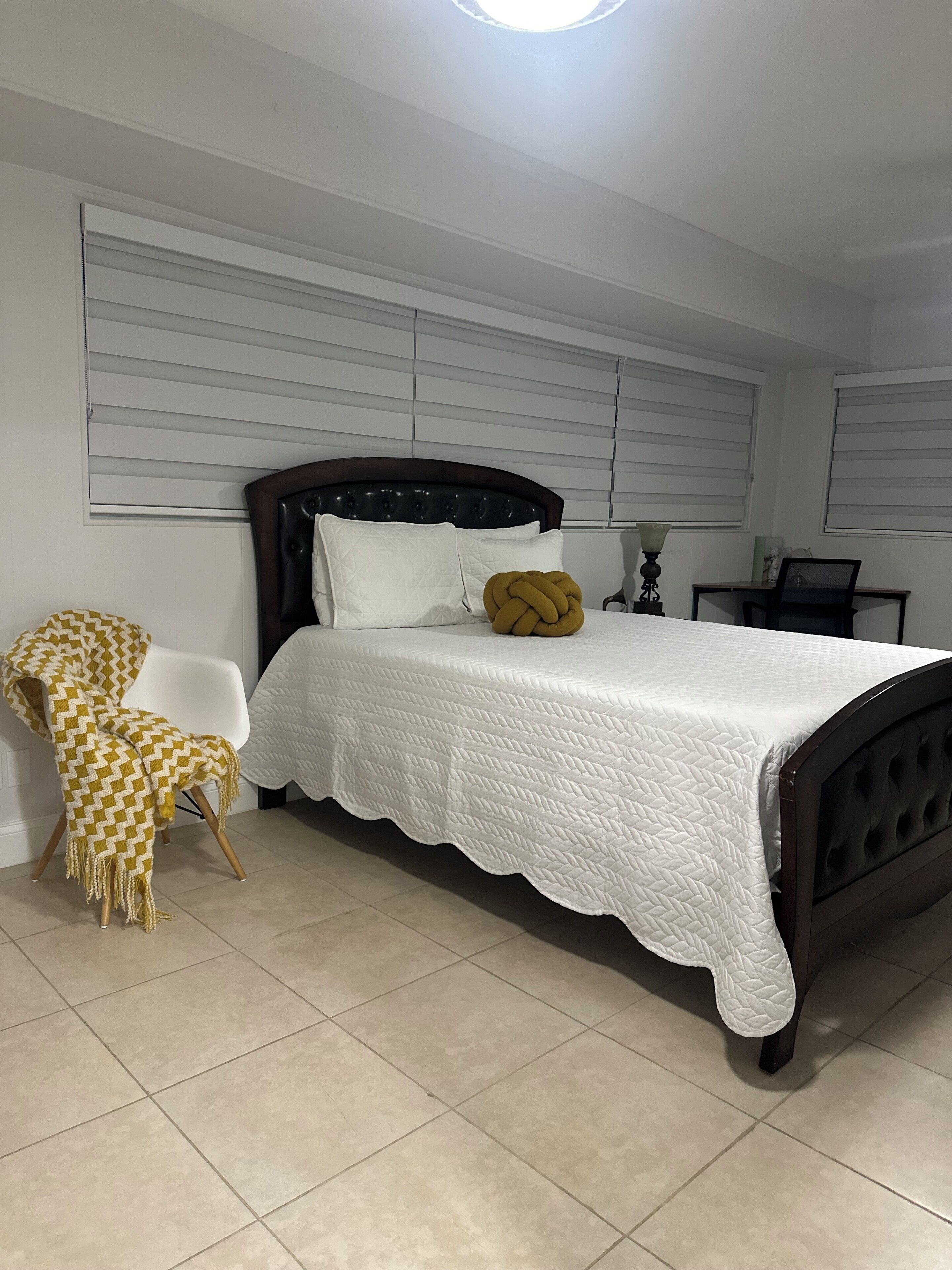 A bedroom with a bed, a chair, and a table.