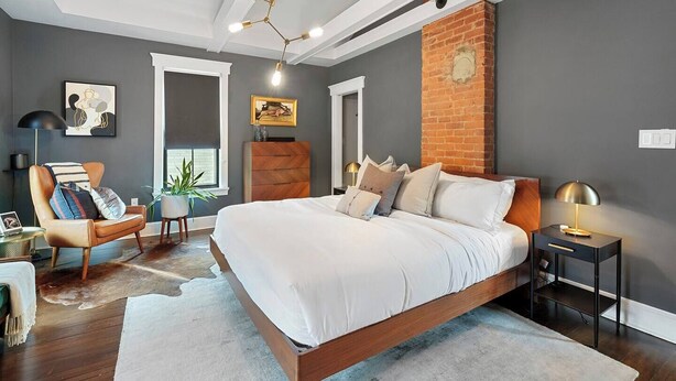 A modern bedroom with a large bed, a wooden nightstand, a chair, and a floor lamp.