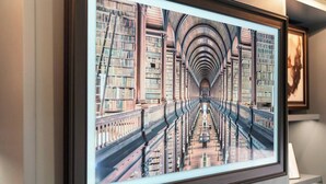 A framed photograph of a library interior with bookshelves and a central aisle.