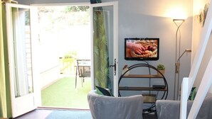 Ein Zimmer mit einer Schiebetür zum Patio, einem an der Wand montierten Fernseher und einem kleinen Regal mit Dekoration.