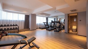 A spacious hotel gym with cardio machines, weightlifting equipment, and a mirror wall. - Dengting Hotel (Haikou)