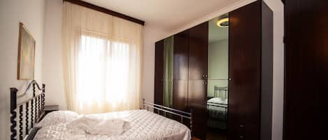 A bedroom with a bed, a wardrobe, and a mirror.