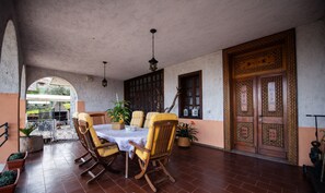 Un patio con mesa y sillas, plantas en macetas y una puerta de madera decorativa.
