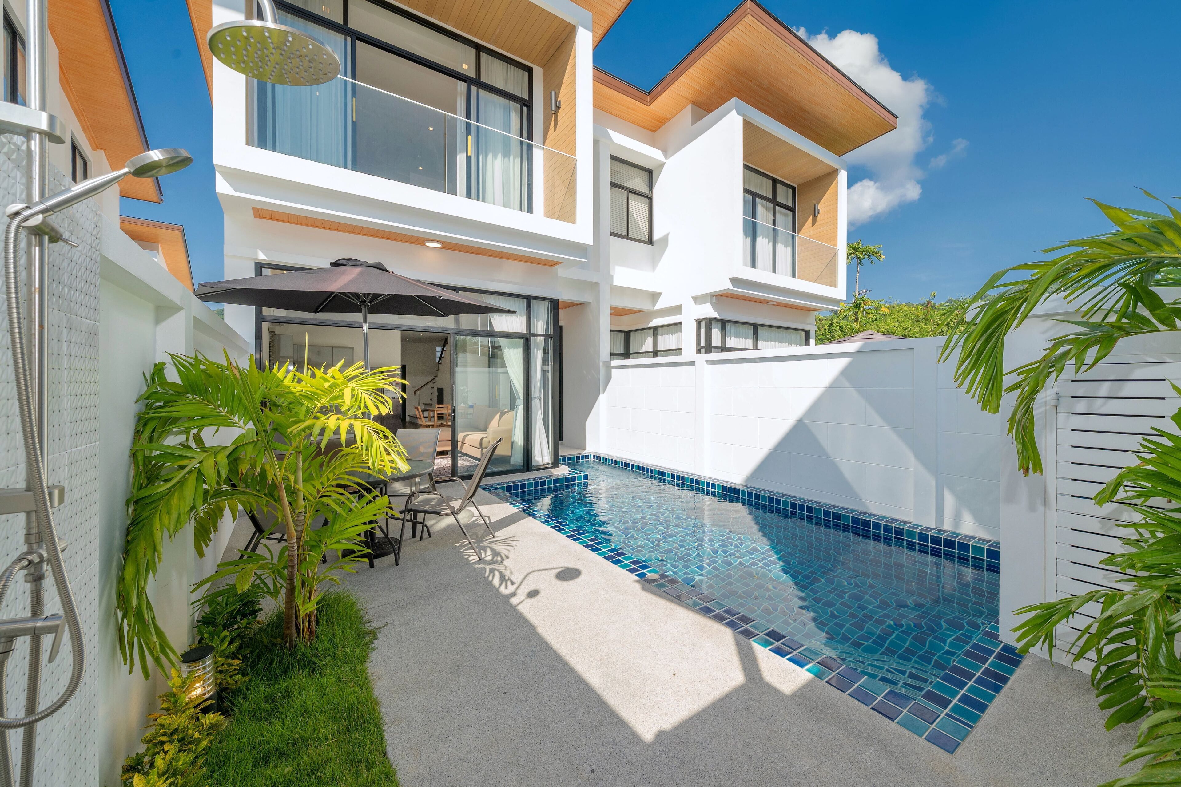 A modern two-story house with a swimming pool, outdoor seating, and a covered patio.