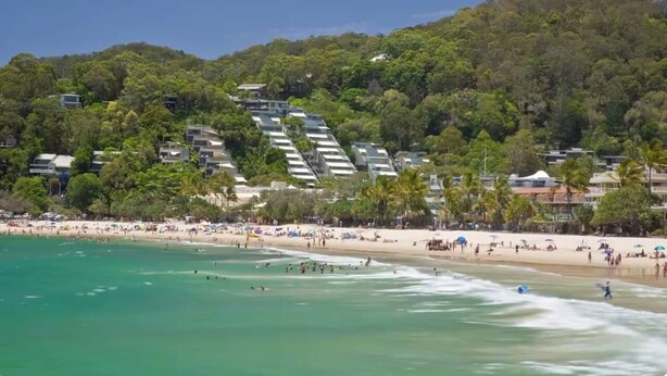 A beach with a view of a hillside with buildings.