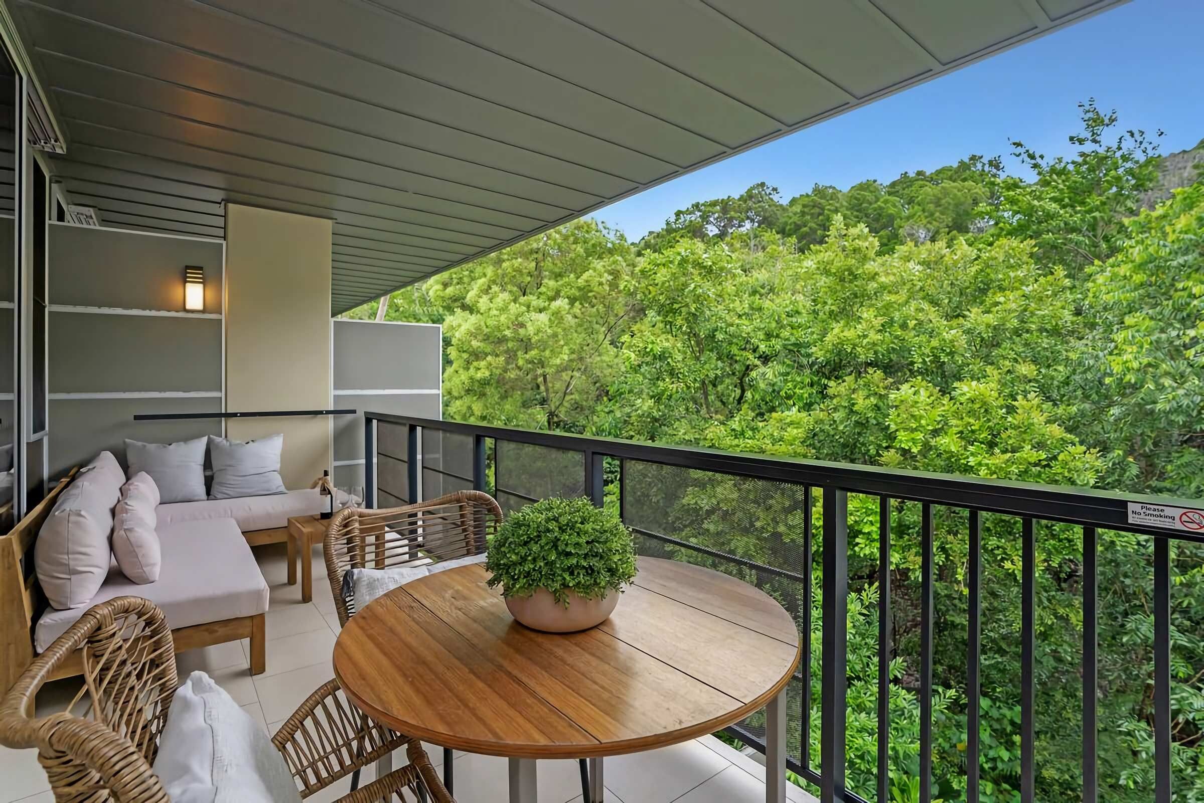 Un balcon avec un canapé, une table et un pot de fleurs.