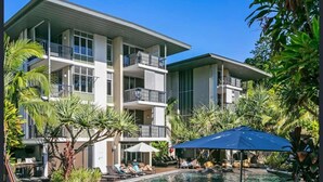 Un hôtel moderne doté d’un espace piscine, comprenant des chaises longues et des parasols.