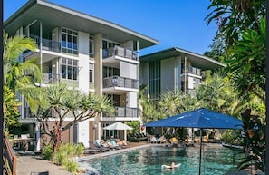 Ein modernes Hotel mit Poolbereich, einschließlich Liegestühlen und Sonnenschirmen.