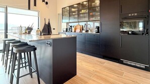 A modern kitchen with a central island, bar stools, and a large window providing a view. - Entire home in Grímsnes og Grafningshreppur, Iceland (Grímsnes  og Grafningshreppur)