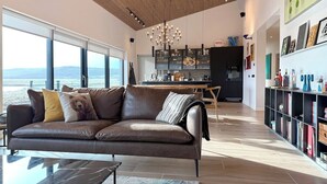 A modern living room with a leather sofa, a dining area, and a kitchen in the background. - Entire home in Grímsnes og Grafningshreppur, Iceland (Grímsnes  og Grafningshreppur)