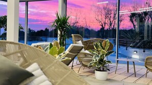 Ein moderner Außenbereich mit Korbmöbeln und Topfpflanzen, mit Blick auf einen Pool.