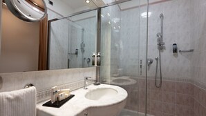 Une salle de bain moderne avec une douche à parois de verre, un lavabo en marbre et un grand miroir.