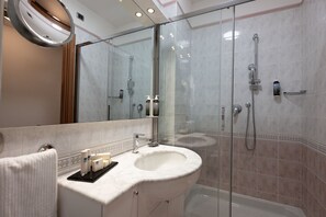 Ein modernes Badezimmer mit einer gläsernen Dusche, einem мраморный Waschbecken und einem großen Spiegel.