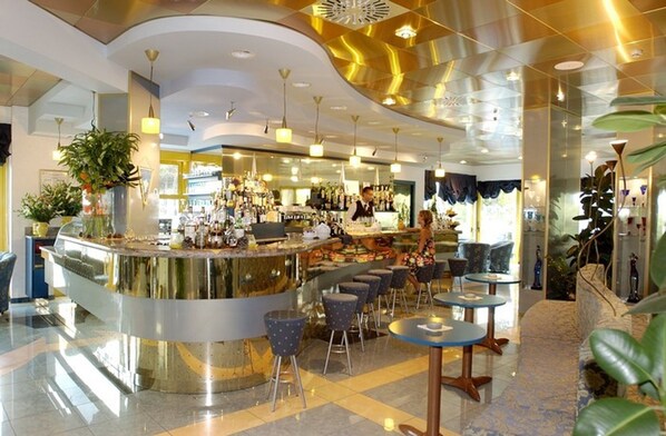 Un espace bar moderne avec un comptoir incurvé, des tabourets de bar et un barman.