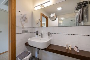 A modern bathroom with a white sink, a mirror, and a towel rack.