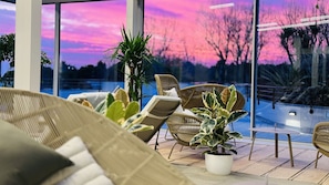 Ein moderner Außenbereich mit Korbmöbeln und Topfpflanzen, mit Blick auf einen Pool.