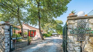 A stone gate with a sign reading "La Roca Residence" leading to a gravel driveway.