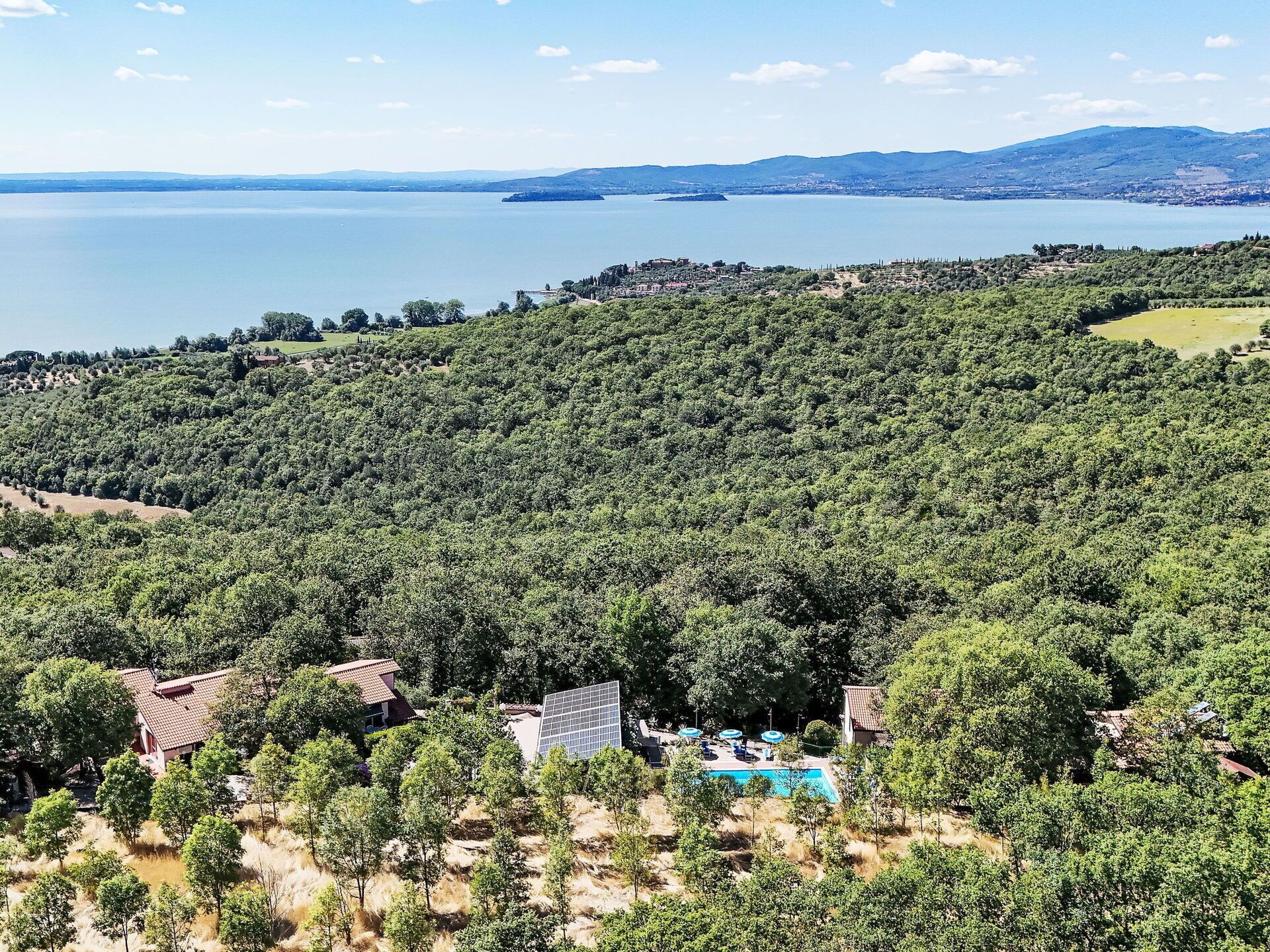 Ein Resort mit Schwimmbad, umgeben von dichtem Wald und Blick auf ein großes Gewässer.
