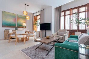 A modern living room with a wooden coffee table, a green sofa, and a TV on a stand. - Unique Apt. With Balcony Cordoba. Templo Romano (Córdoba)