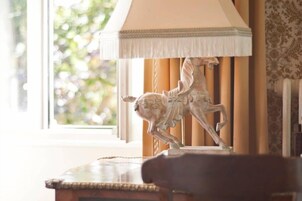 Una lámpara con pantalla blanca y base decorativa con un caballo y un perro.