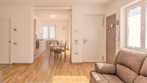 A modern apartment with a wooden floor, a dining area with a table and chairs, a sofa, and a kitchen in the background. - Beautiful apartment for 4 guests with WIFI, A/C, TV, patio and panoramic view (Dro)