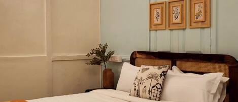 A neatly made bed with a white and orange blanket, a wooden headboard, and three framed pictures on the wall.