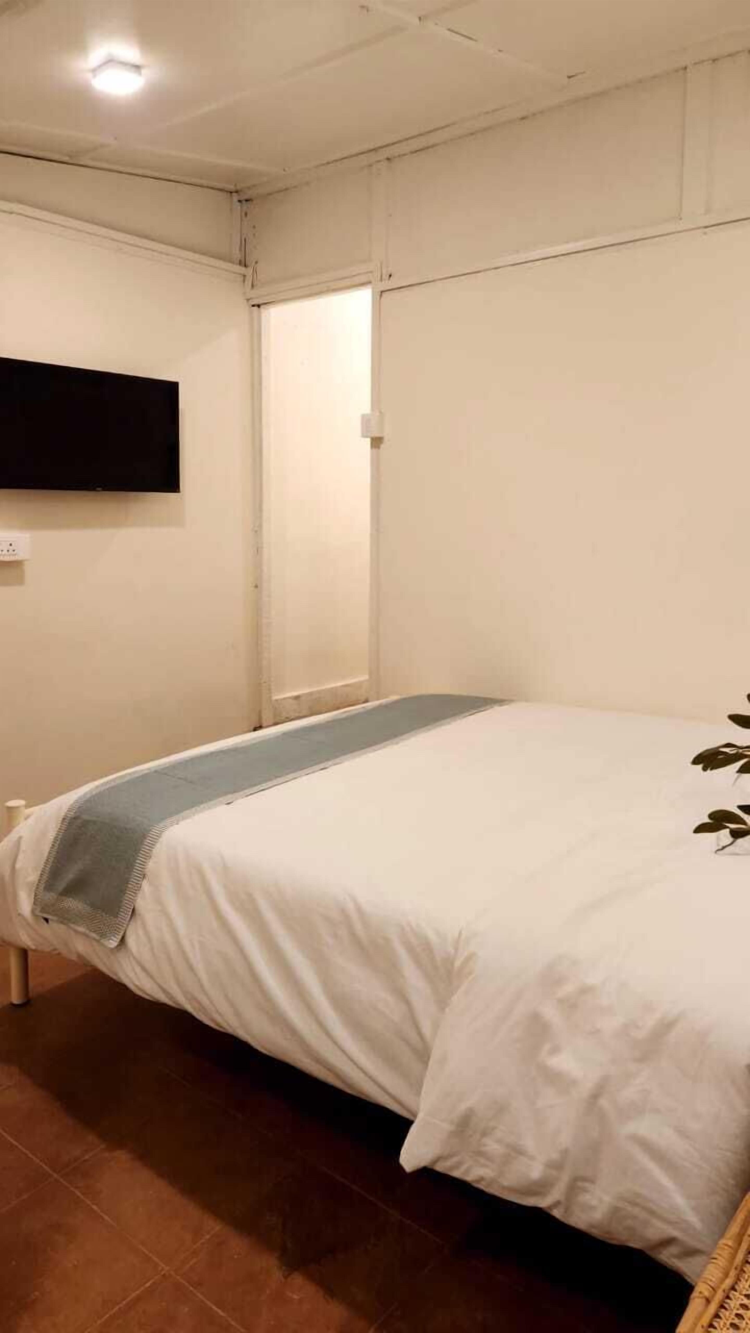 Een slaapkamer met een bed, een wandtelevisie en een deur.