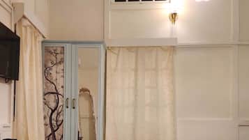 A bedroom with a bed, a wardrobe, a desk, and a hanging light fixture.