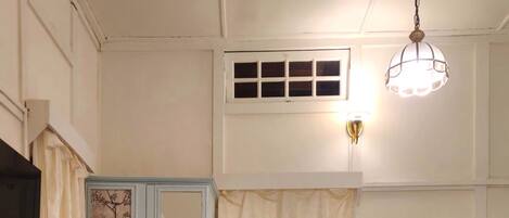 A bedroom with a bed, a wardrobe, a desk, and a hanging light fixture.
