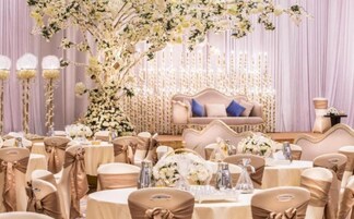 Un espace événementiel formel, équipé de tables rondes, de chaises et d’une scène avec un canapé.