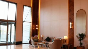 Un hall d’entrée spacieux, aménagé avec un ensemble de canapés, une table basse et une table d’appoint avec une lampe.