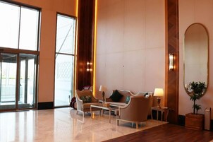 Un hall d’entrée spacieux, aménagé avec un ensemble de canapés, une table basse et une table d’appoint avec une lampe.